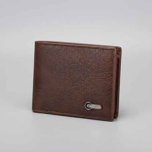 Brown leather wallet on a wooden surface with a pen next to it