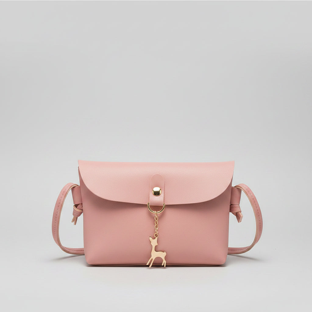 Pink handbag with a decorative charm held by a hand on a magazine background