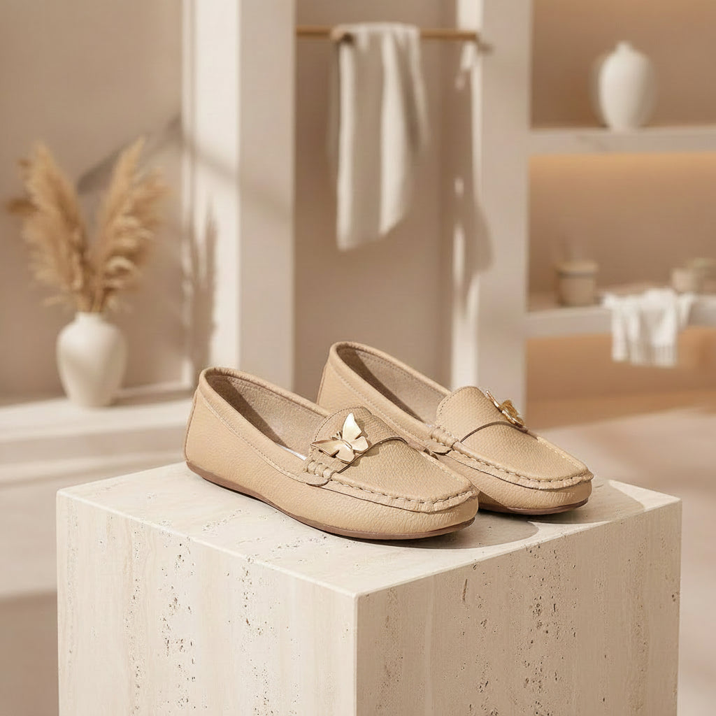 Beige loafers with decorative bows on a wooden surface