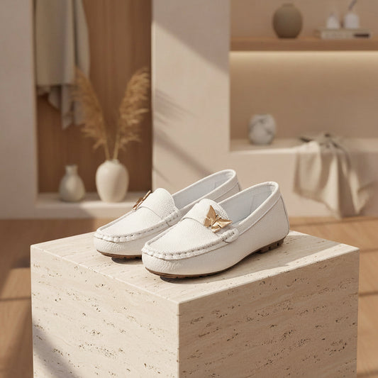 White loafers with gold butterfly accents on a wooden surface