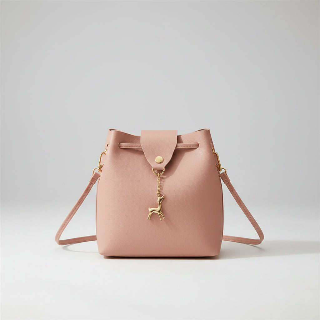 Pink handbag with a gold deer charm on a white surface