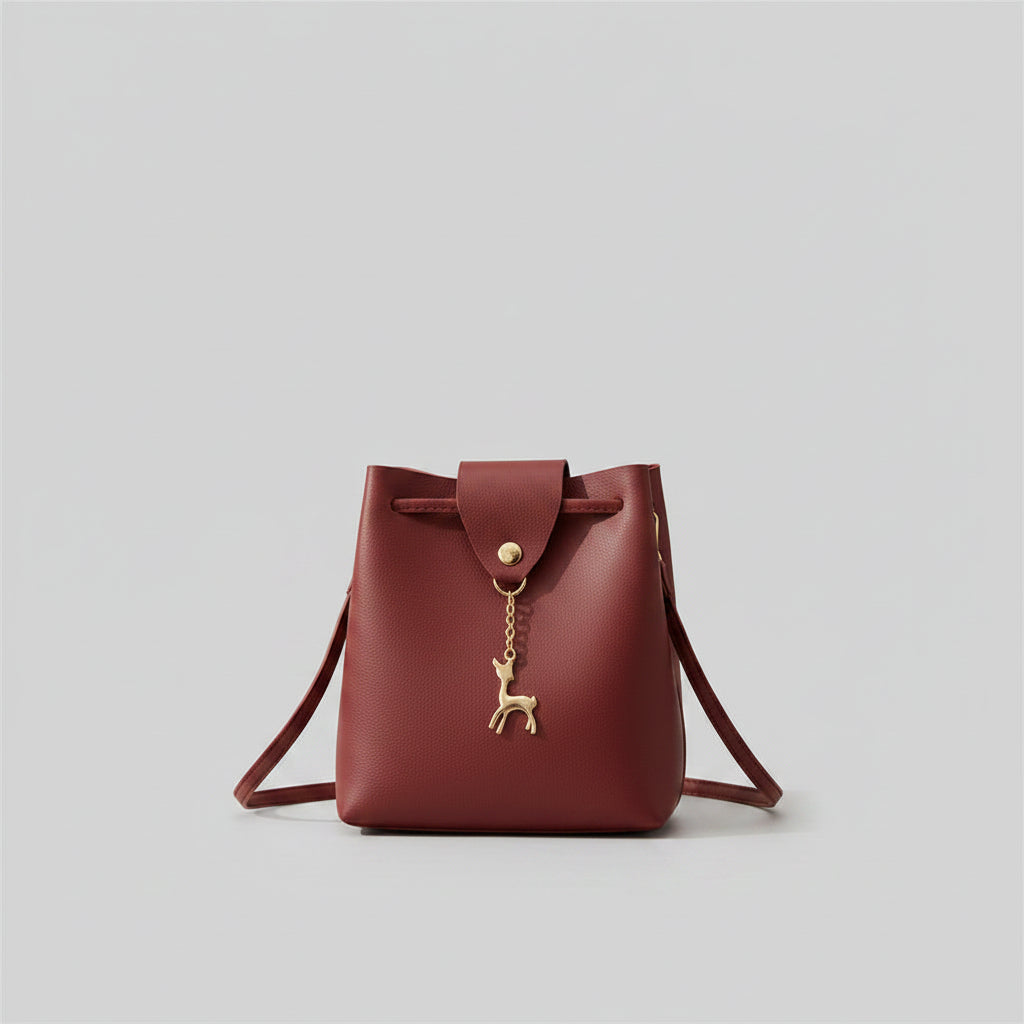Red handbag with a gold deer charm on a white background