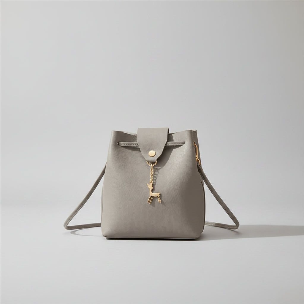 Gray handbag with a deer charm on a white background