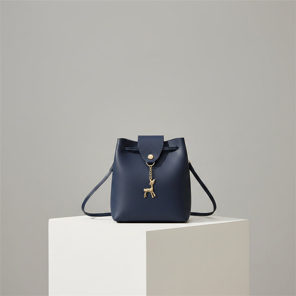 Navy blue handbag with a gold deer charm on a white background