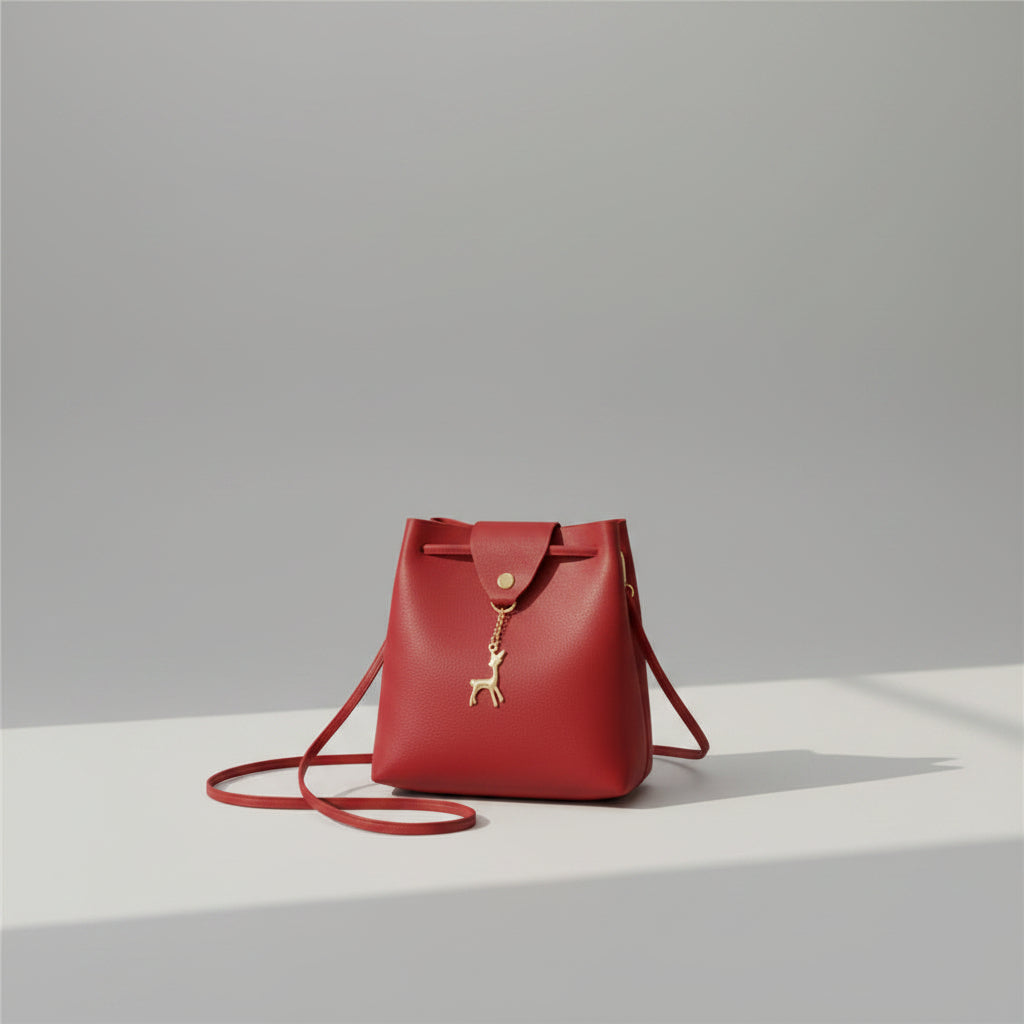 Red handbag with a gold deer charm on a white surface