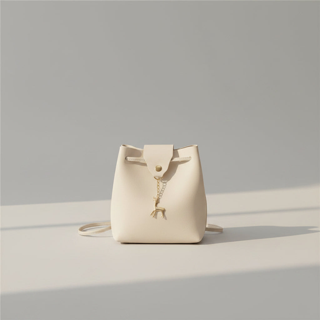 White handbag with a gold charm on a white surface